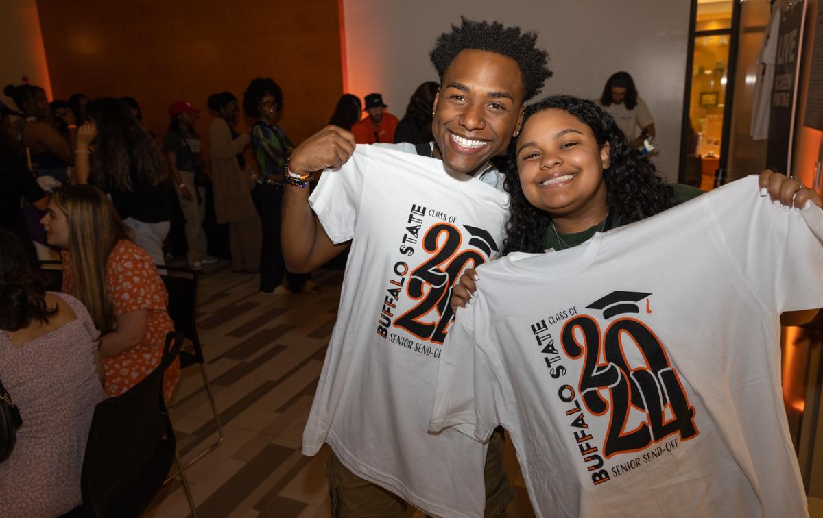 Two smiling students holding Buffalo State Class of 2024 T-shirts