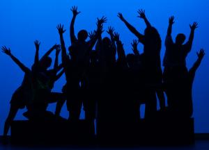 Silhouetted images of people clusted together with arms and fingers outstretched