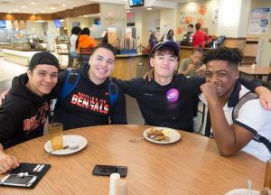 Four students sitting at a round table in the food court