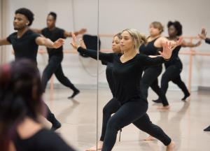 Students in a modern dance class dressed in black leotards 