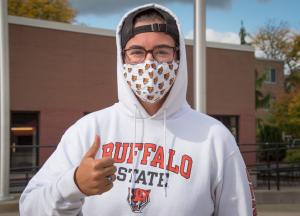 Masked student wearing a Buffalo State sweatshirt giving the thumbs-up sign