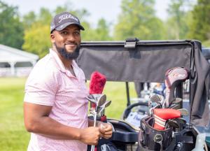 Man standing with golf clubs by a golf cart