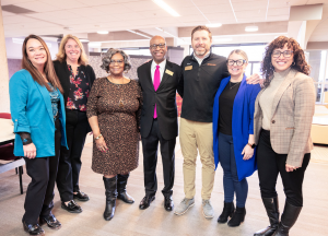 A group of administrative professionals stand with the Dr. Durand