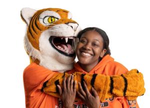 Smiling Buffalo State student gets a hug from mascot Benji