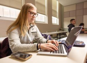 Student sitting at a laptop in a classroom