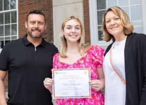 A student with two adults and honors certificate