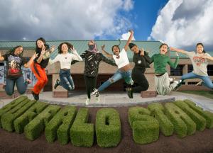 Photo illustration of students jumping in the air in front of commencement garden by Sports Arena