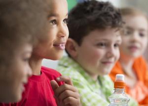 Faces of four young children, smiling and engaged in learning