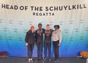Rowers and their coaches pose under banner that reads Head of the Schuylkill Regatta