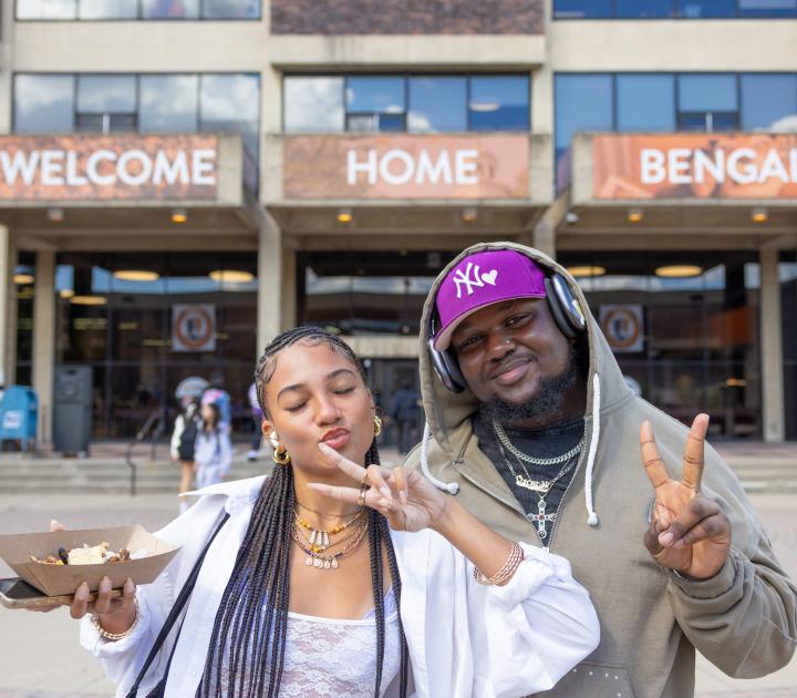 Two students standing in front of E.H. Butler Library and a sign that reads Welcome Home Bengals