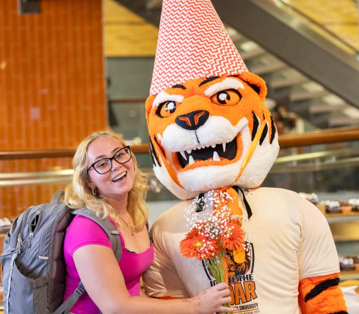 A female student poses with Benji Bengal mascot